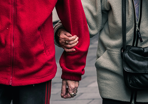 Two people's arms in coats shown holding hands