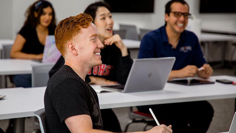 students sitting at desks in classroom smiling