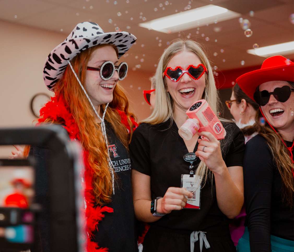 three ladies posing with props at a photo booth at an HSC event 