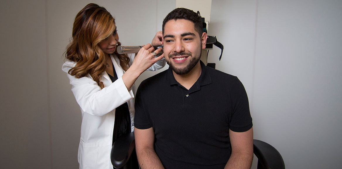 A Ph.D in Rehabilitation Science student checks the hearing of a patient during an examination.