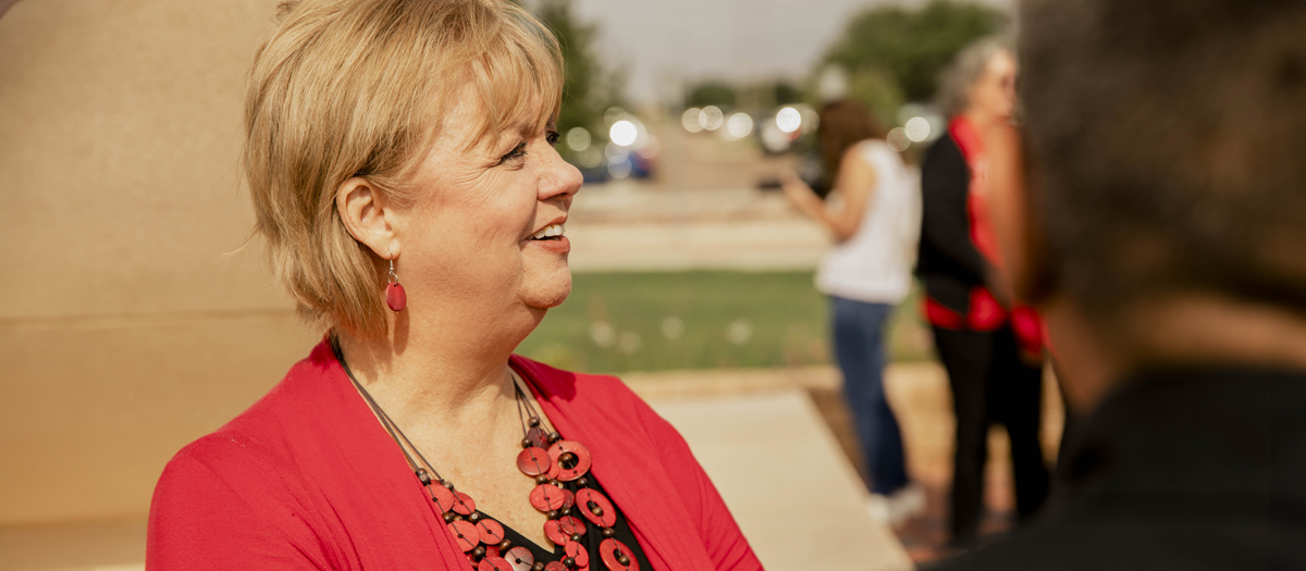 TTUHSC team member in her red sweater, smiling to another person