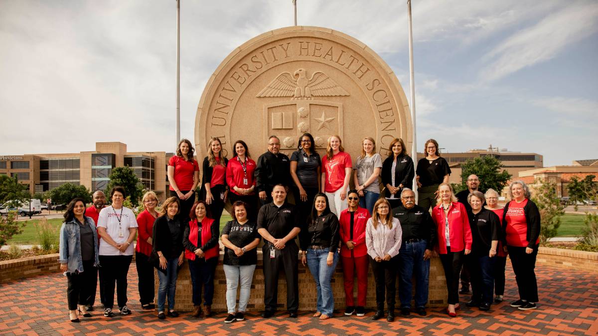 ttuhsc team members in front of the university seal