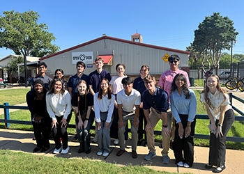 A group of TTUHSC Summer Enrichment students are standing in front of the Open Door building smiling