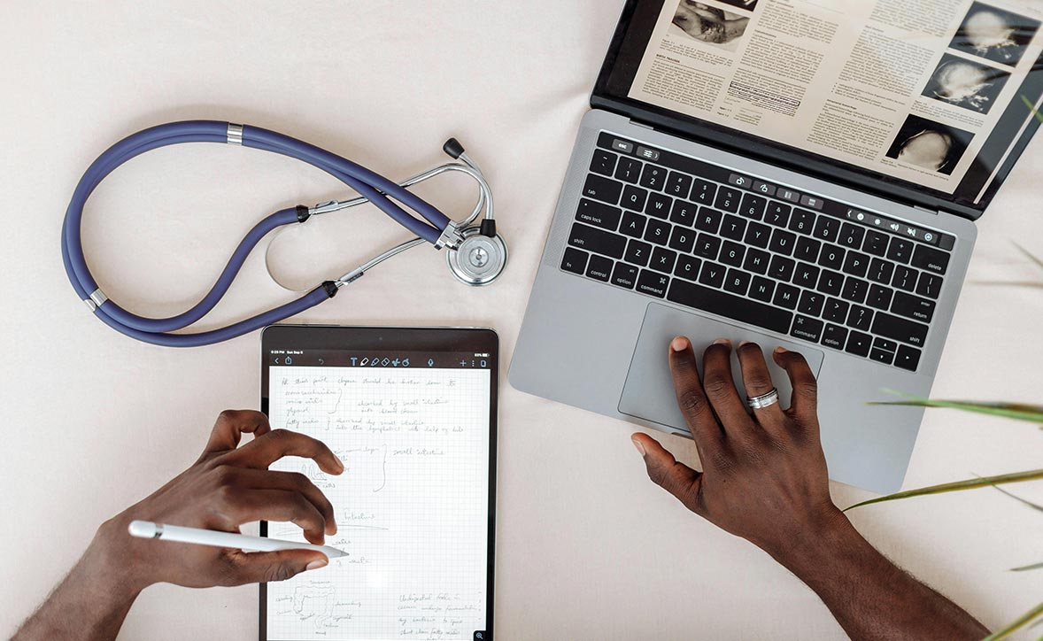 hands writing on a tablet and utilizing a computer