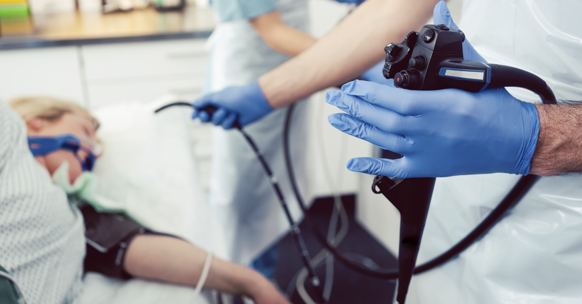 Image of a doctor holding a gastro scope with patient and nurse in background