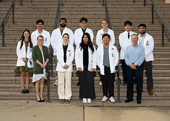 TTUHSC medical education students standing in white lab coats infront of the Lubbock campus stairway outdoors