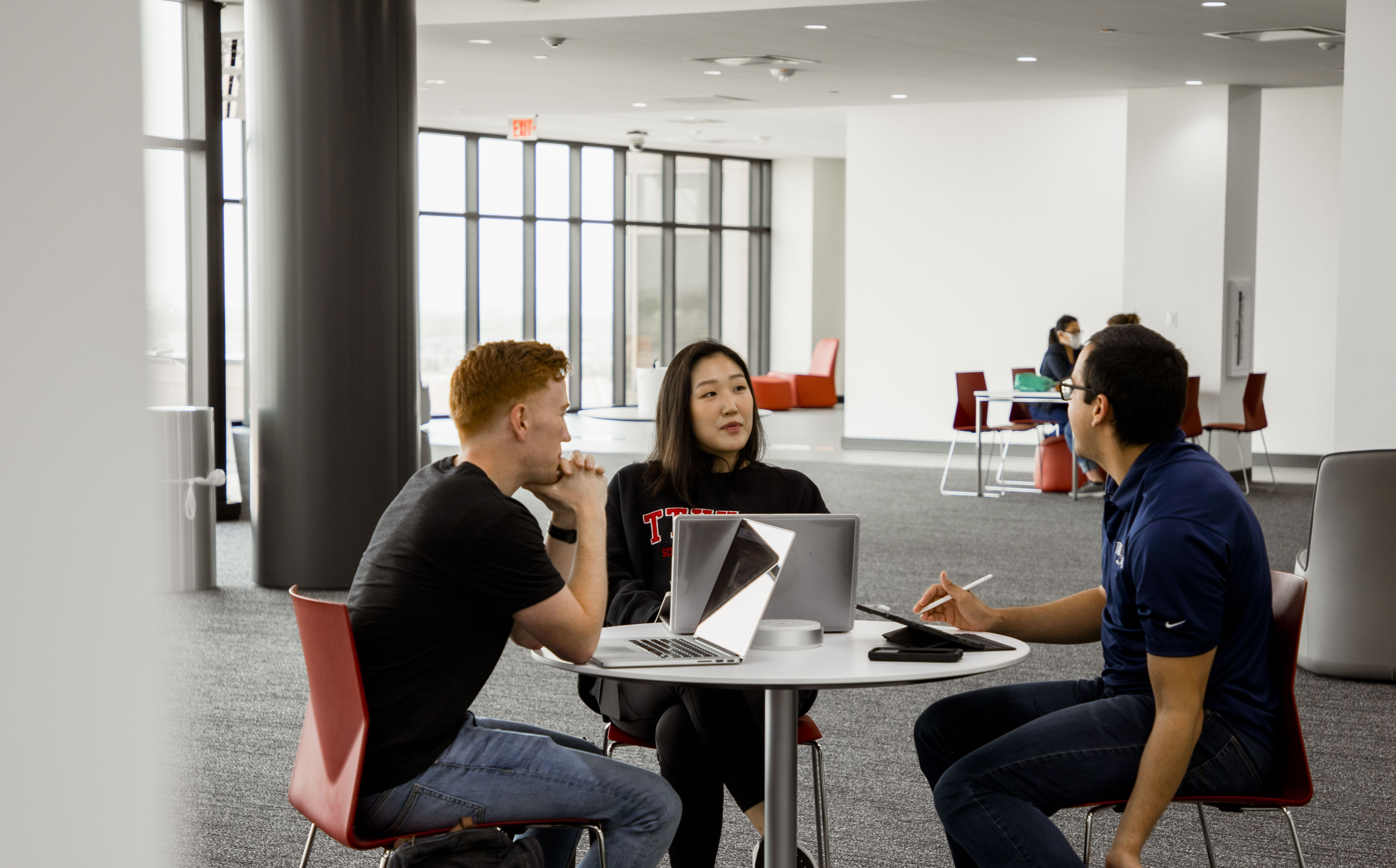three students sitting at a table in the SOM classroom