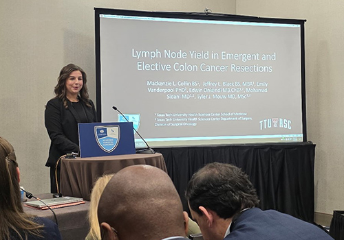 TTUHSC student standing at a podium presenting next to a screen to an audience 