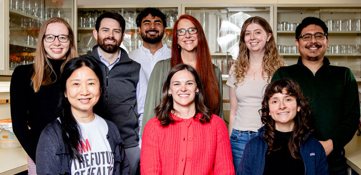 2025 Rumbaugh Lab staff members with six standing in a lab smiling and three members sitting infront of the six smiling