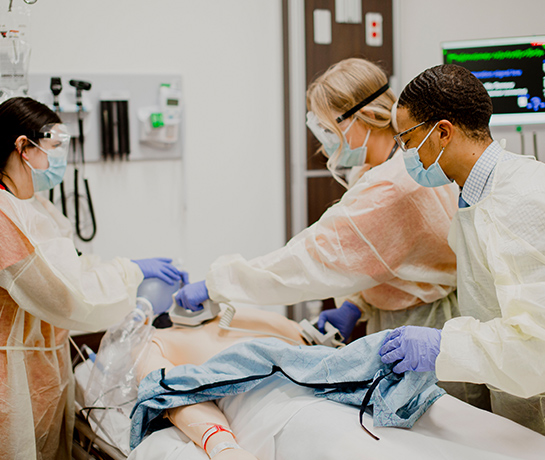 TTUHSC nursing students in PPE gear standing over SIM Center mannequin applying hands on techniques