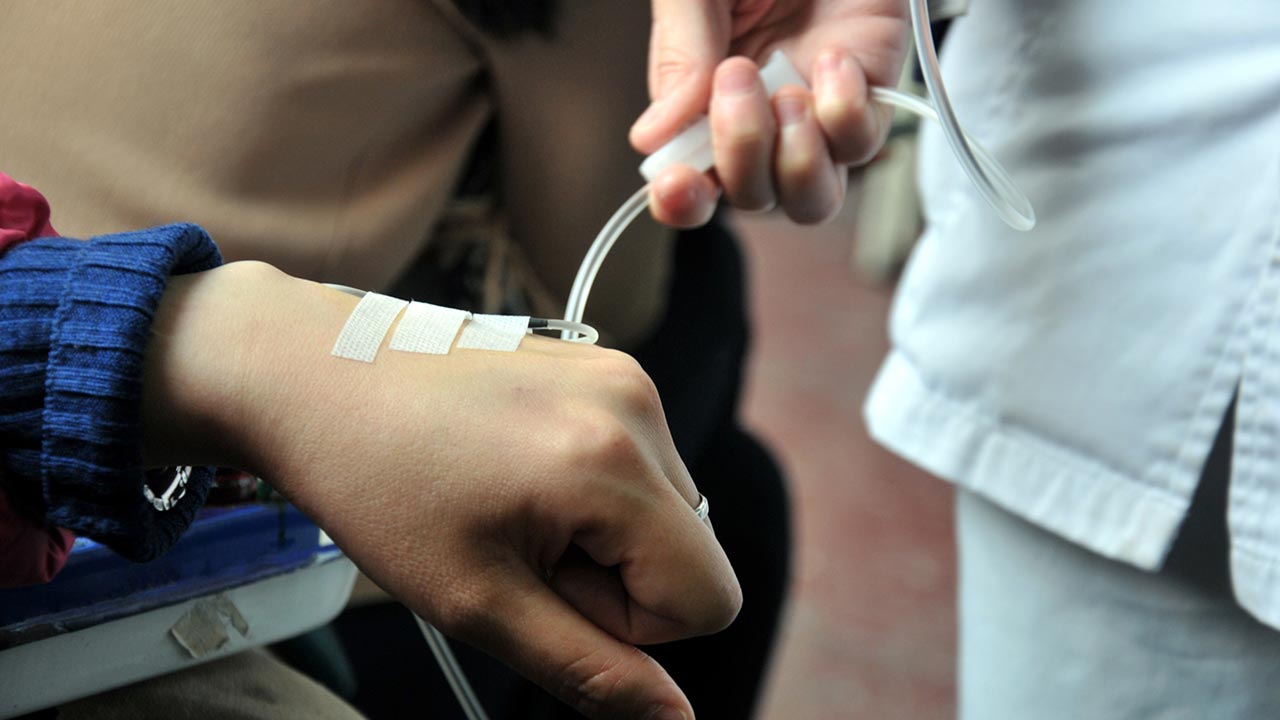 The provider's hands starting an IV in a patient's hand