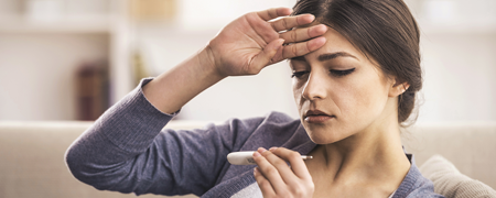 woman with a fever and a thermometer