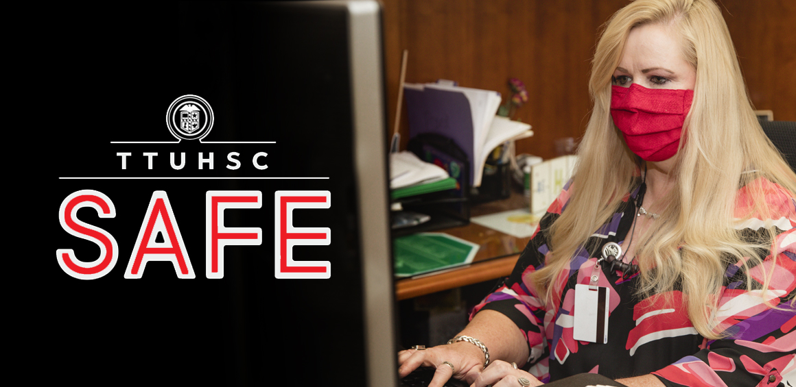 team member working at desk on campus with mask on